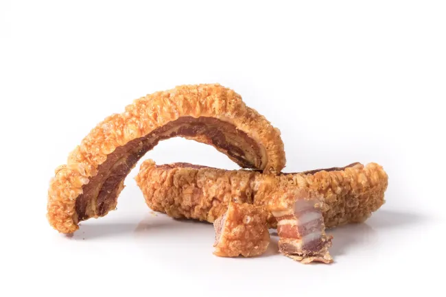 Dos trozos de cerdo frito sobre una superficie blanca.