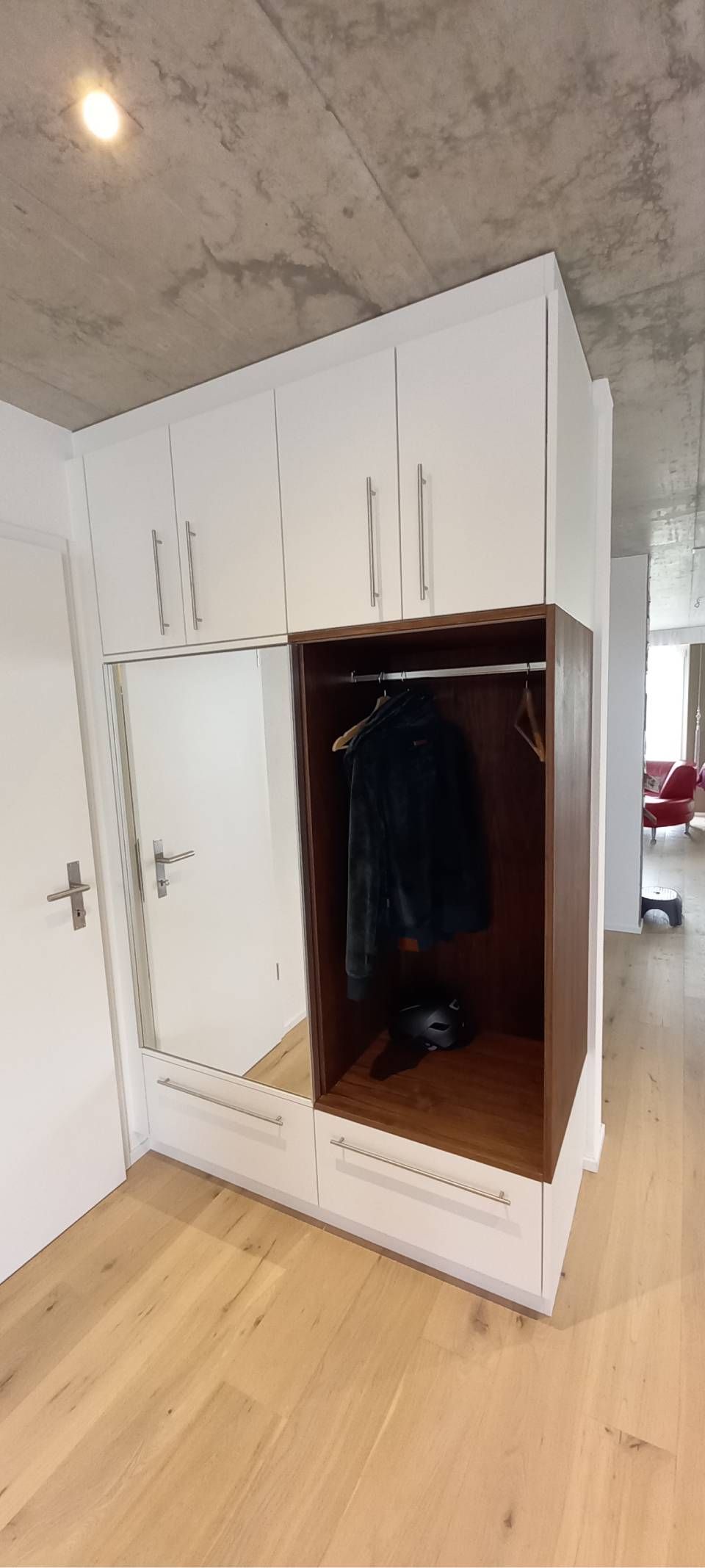 Weisser Kleiderschrank mit offener Tür und hängender Kleidung in einem modernen Zimmer mit Holzboden und Marmorwänden