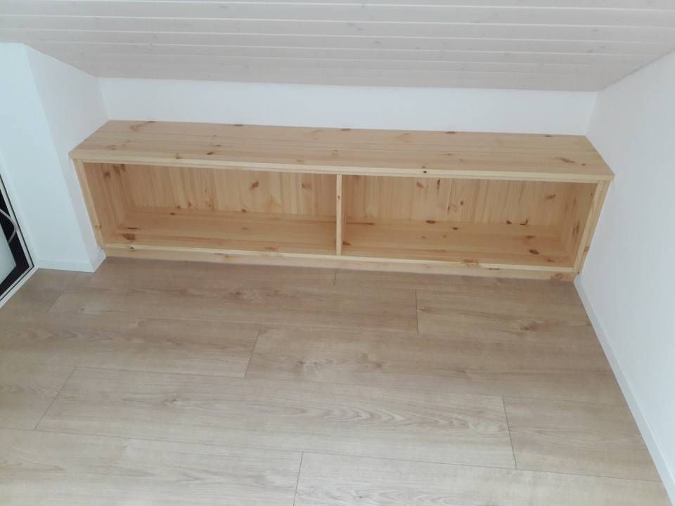 Holzaufbewahrungsbank unter einer schrägen weissen Decke in einem leeren Raum