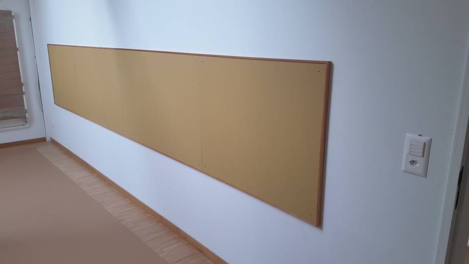 Lange, beige Wandpaneele entlang einer Flurwand neben einem Lichtschalter.