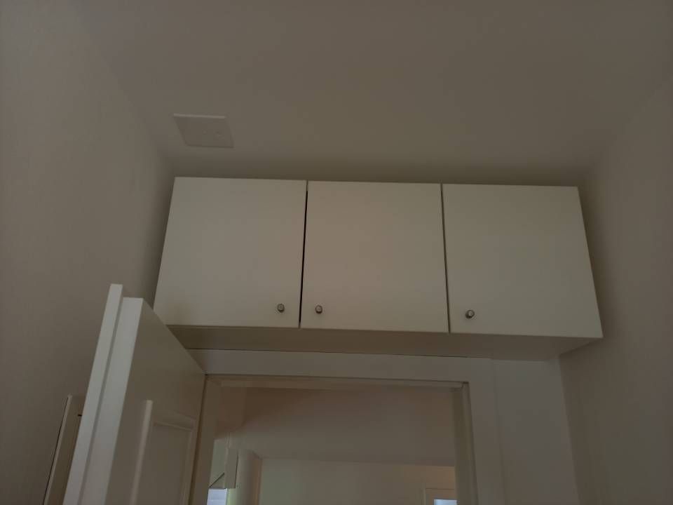 Weisser Schrank über einer Türöffnung in einer schlichten Innenwand