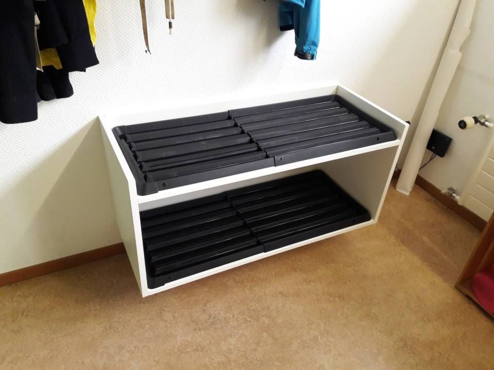 Weisses Fächerregal mit schwarzen Aufbewahrungsboxen in einem Kleiderschrank oder Eingangsbereich