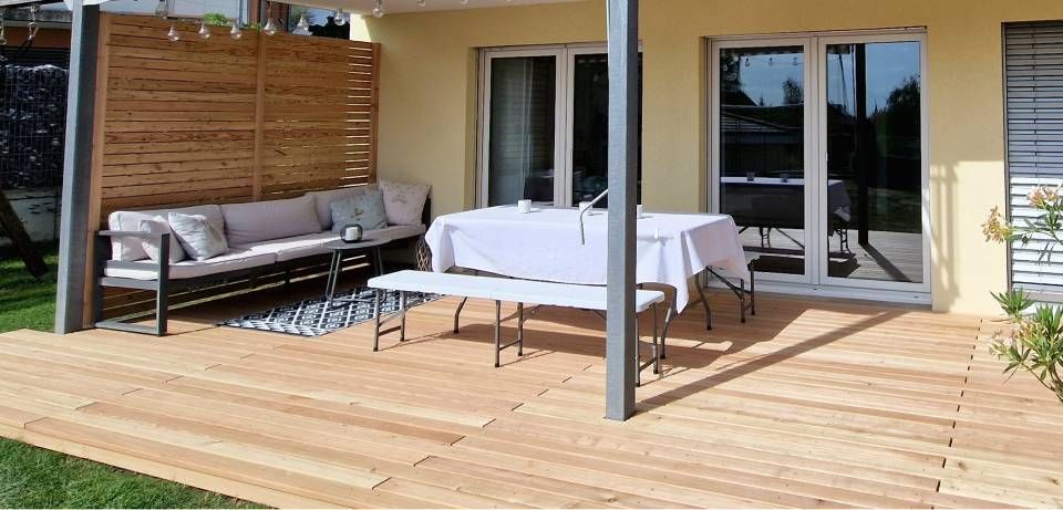 Überdachte Holzterrasse mit Gartensofa, Esstisch und Glasschiebetüren