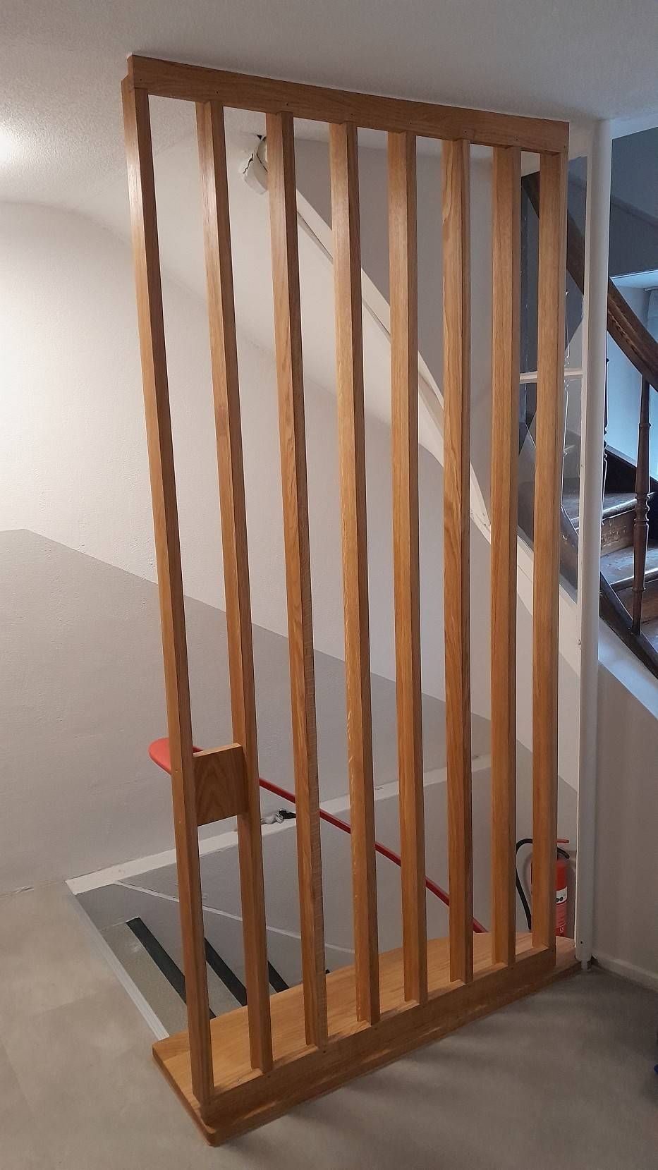 Treppenabsperrung oder -gitter aus Holzlatten, das in einem Flur neben einer Treppe angebracht ist.