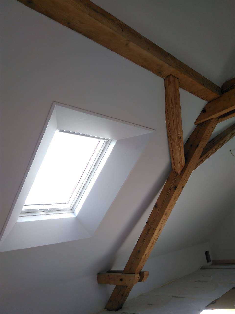 Oberlicht in einer schrägen weissen Decke mit sichtbaren Holzbalken und -streben
