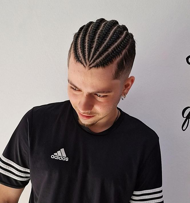 Un hombre que lleva una camiseta negra de adidas y tiene trenzas en el pelo.