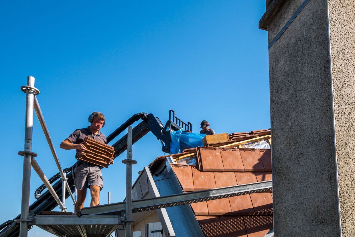 Couvreur en train de porter des tuiles en terre cuite