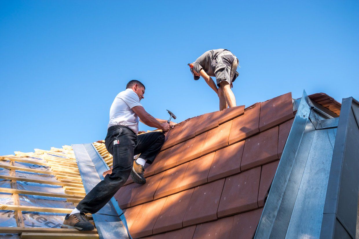 Deux couvreurs en train de réaliser des travaux de couverture sur un toit