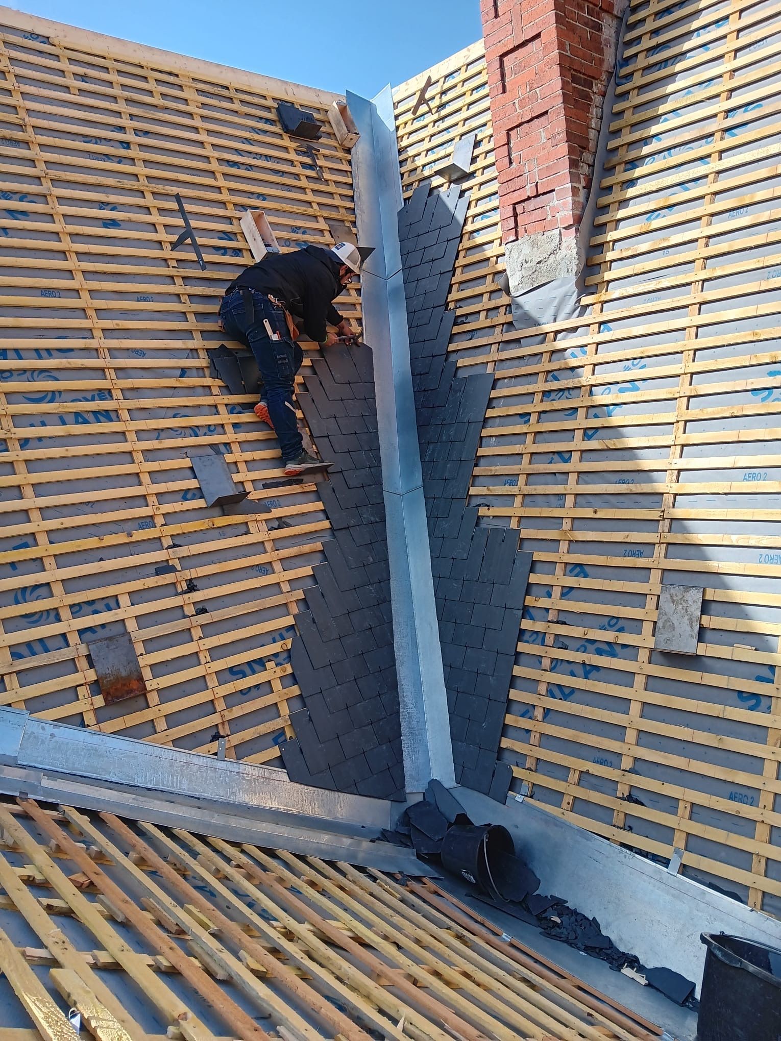 Artisan posant des ardoises sur un toit lors d'une rénovation