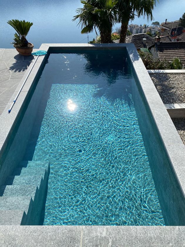 Stretta piscina all'aperto accanto a una ringhiera di vetro, con vista sulle colline al crepuscolo.