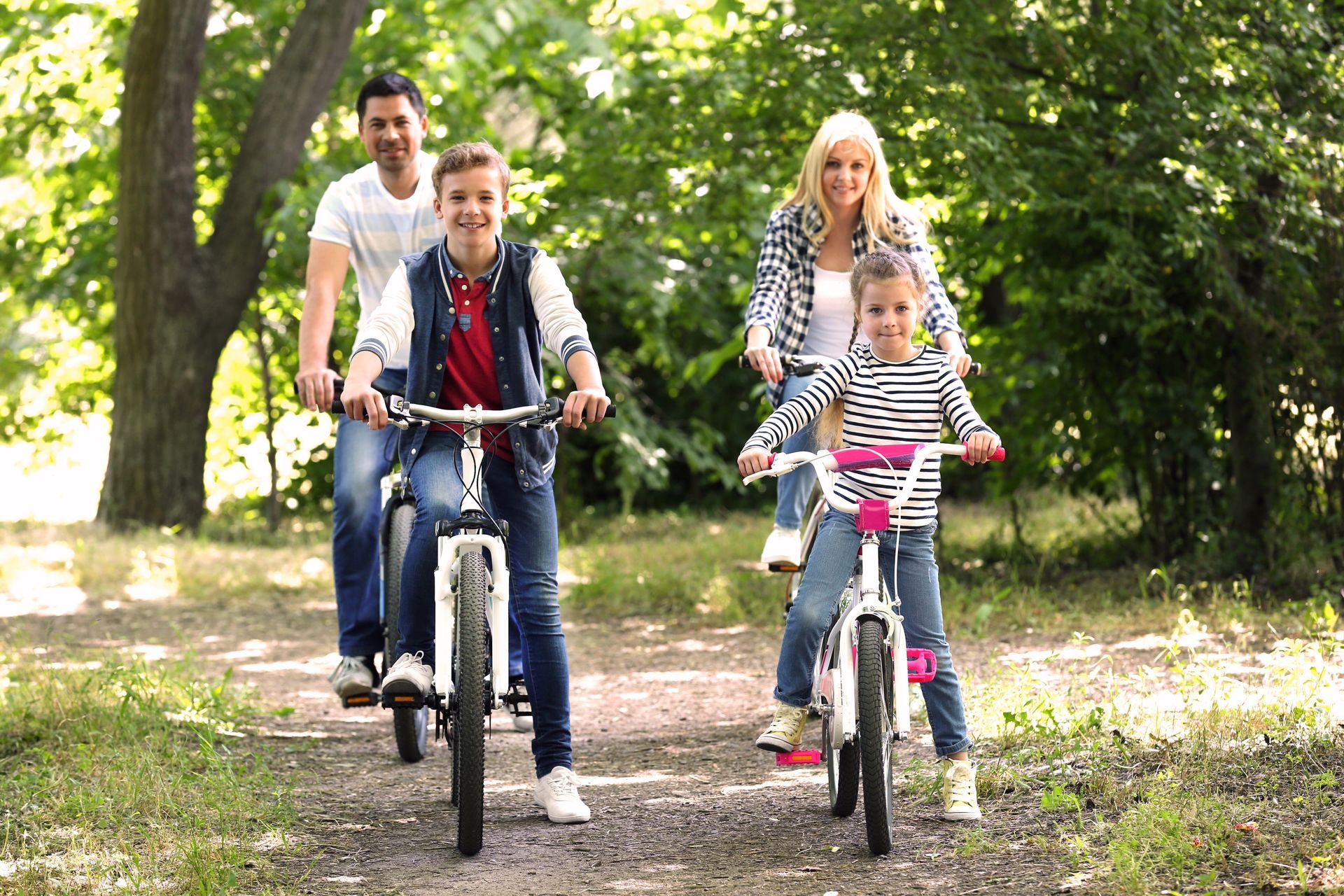 Eine Familie fährt mit Fahrrädern einen Weg im Park entlang.