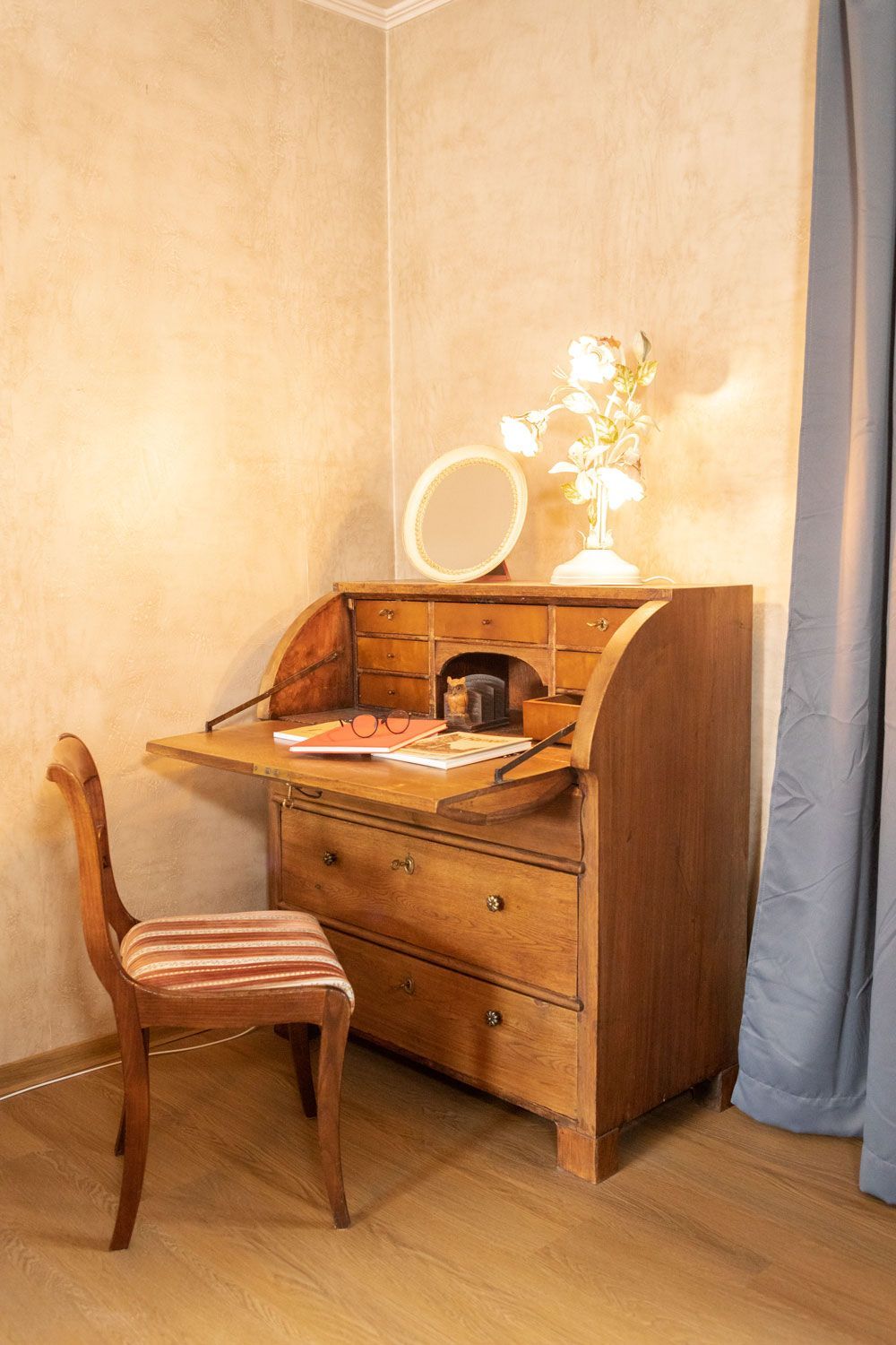 Ein Holzschreibtisch mit einem Stuhl und einem Spiegel in einem Zimmer.