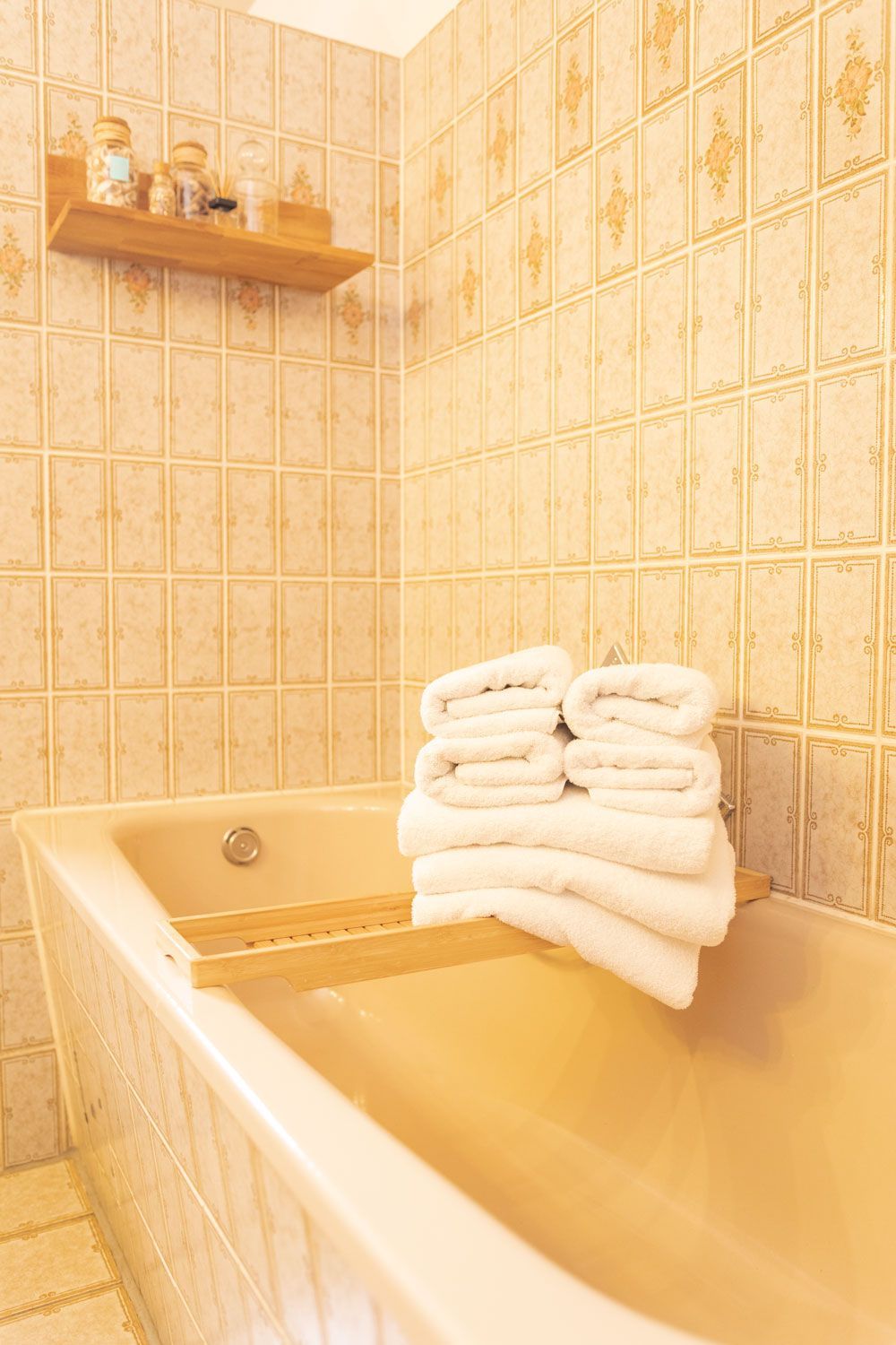 Auf einer Badewanne liegt ein Stapel Handtücher.