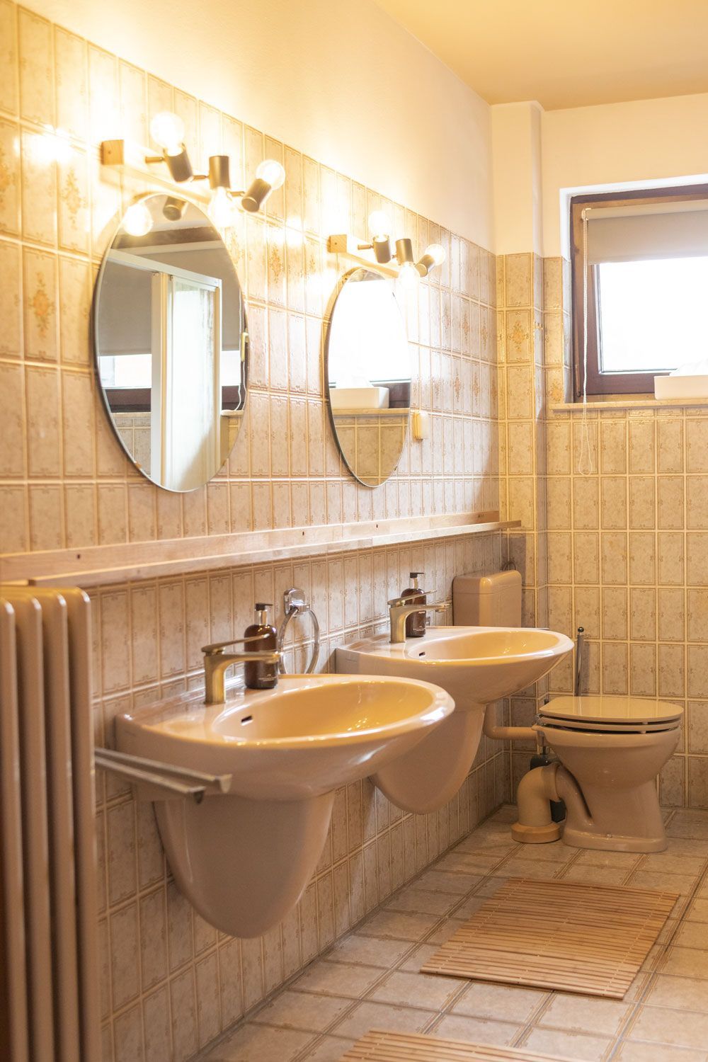 Ein Badezimmer mit drei Waschbecken und einer Toilette.