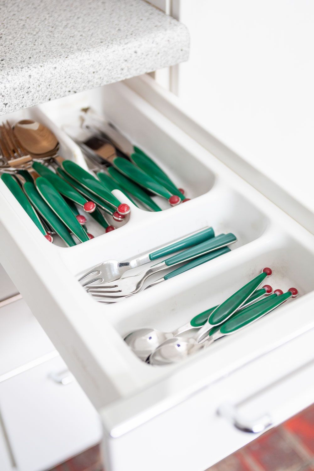 Eine Schublade mit Besteck mit grünen Griffen gefüllt