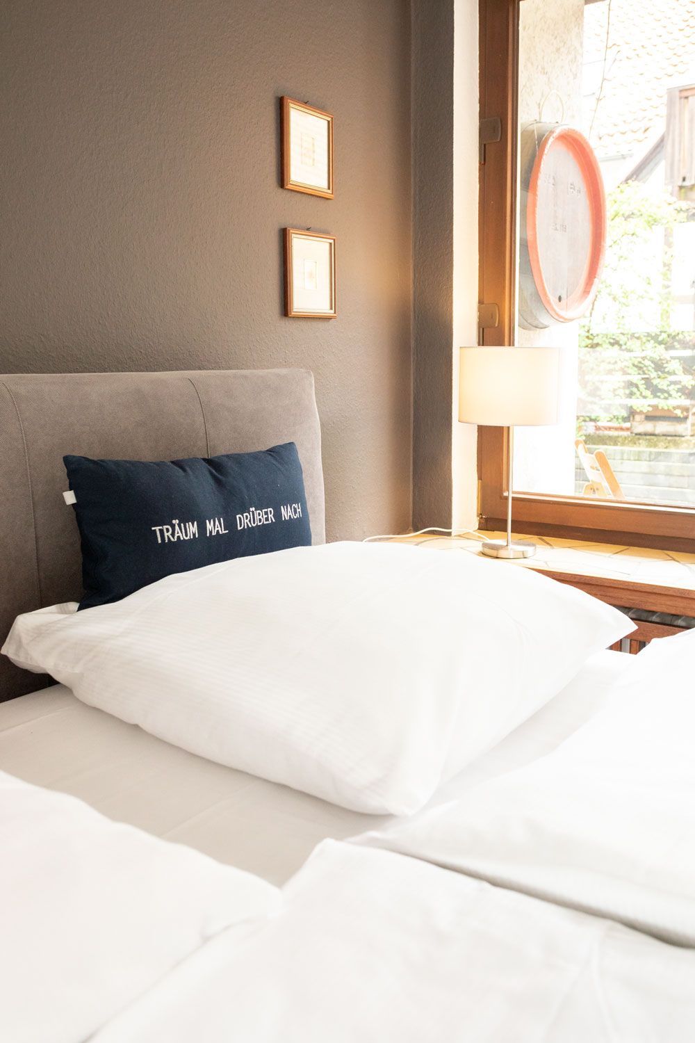 Ein Bett mit weißen Laken und einem blauen Kissen darauf.