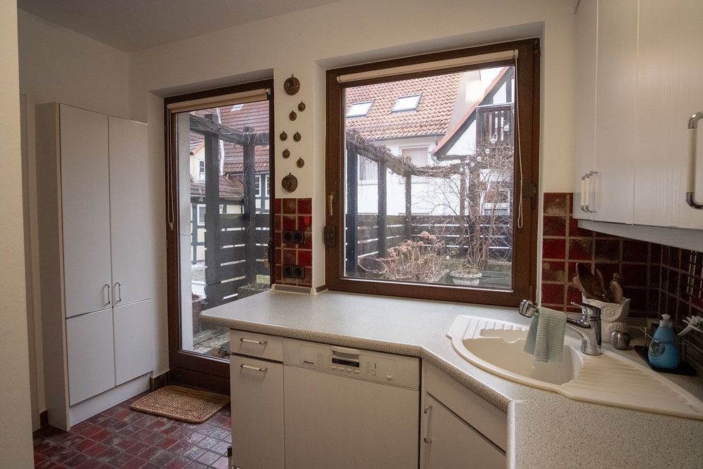 Eine Küche mit weißen Schränken, einer Spüle und einem Fenster.