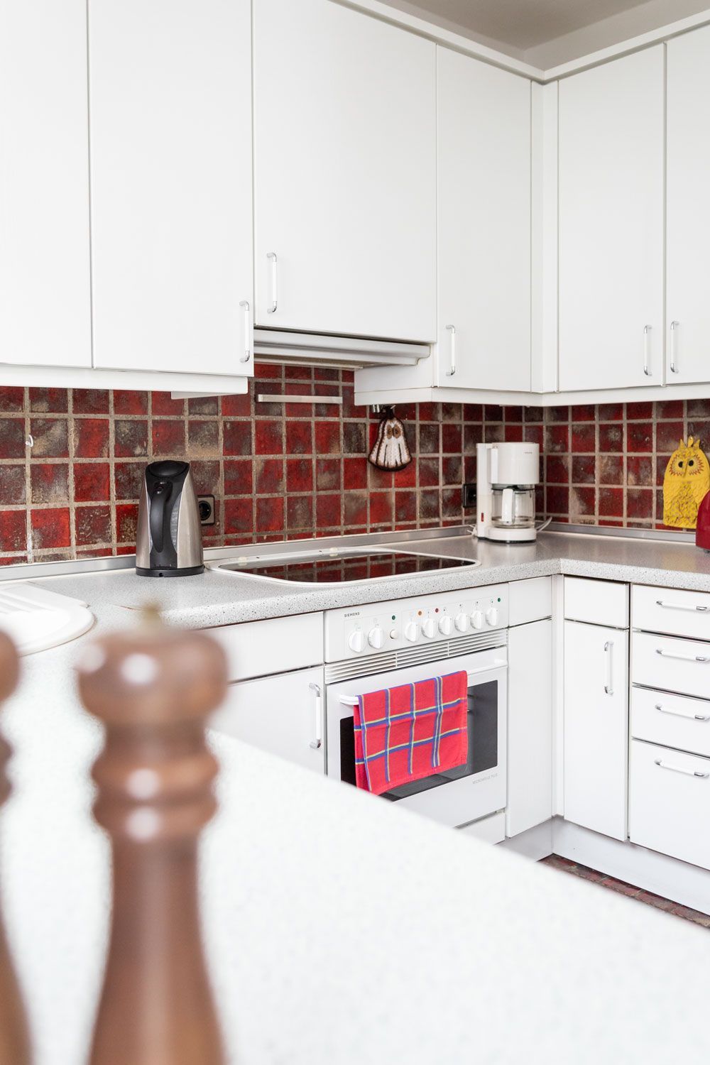 Eine Küche mit weißen Schränken und roten Fliesen an der Wand