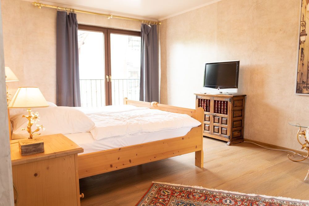 Ein Schlafzimmer mit Bett, Nachttisch, Fernseher und Kommode.