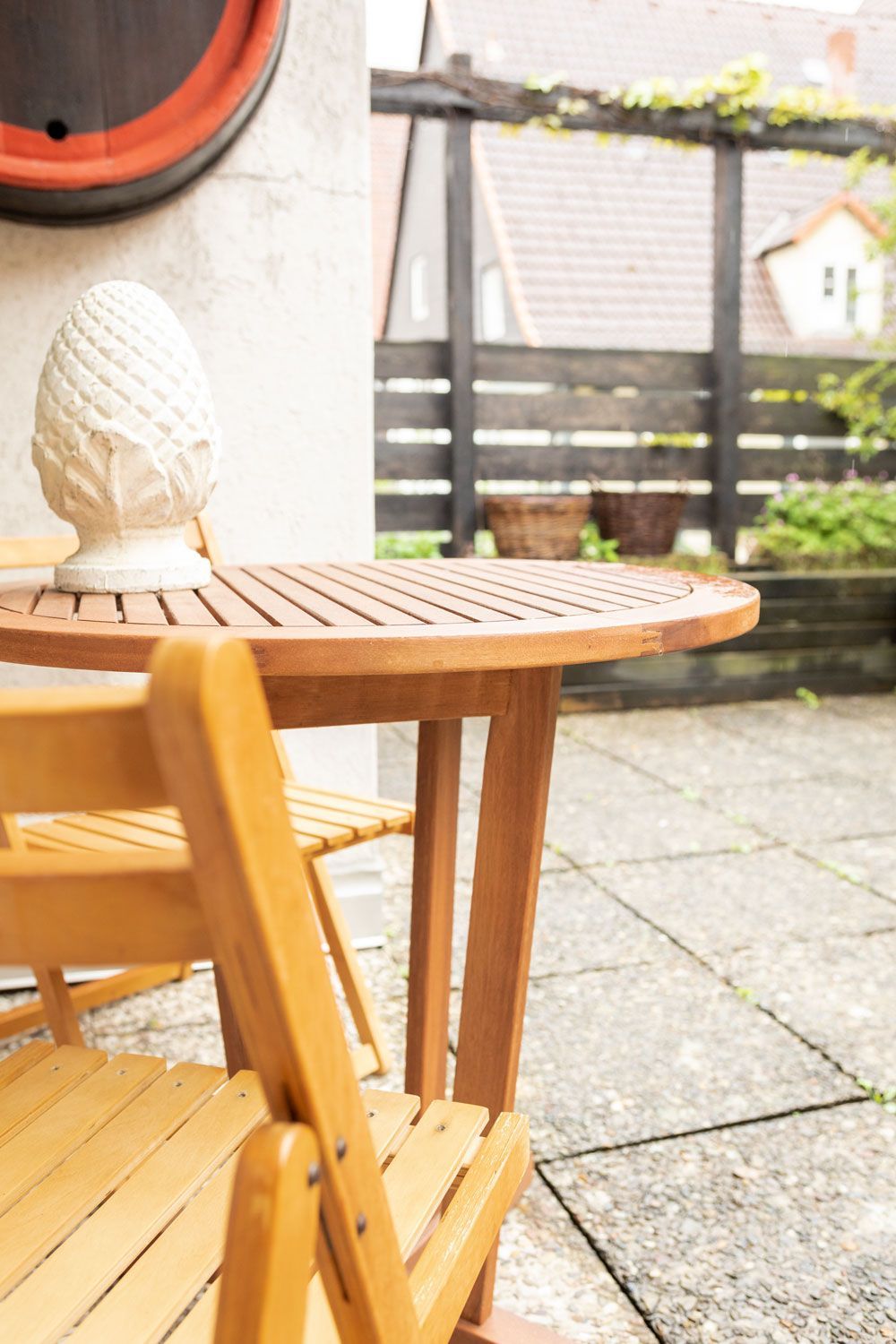 Ein Holztisch und Stühle auf einer Terrasse mit einem Zaun im Hintergrund