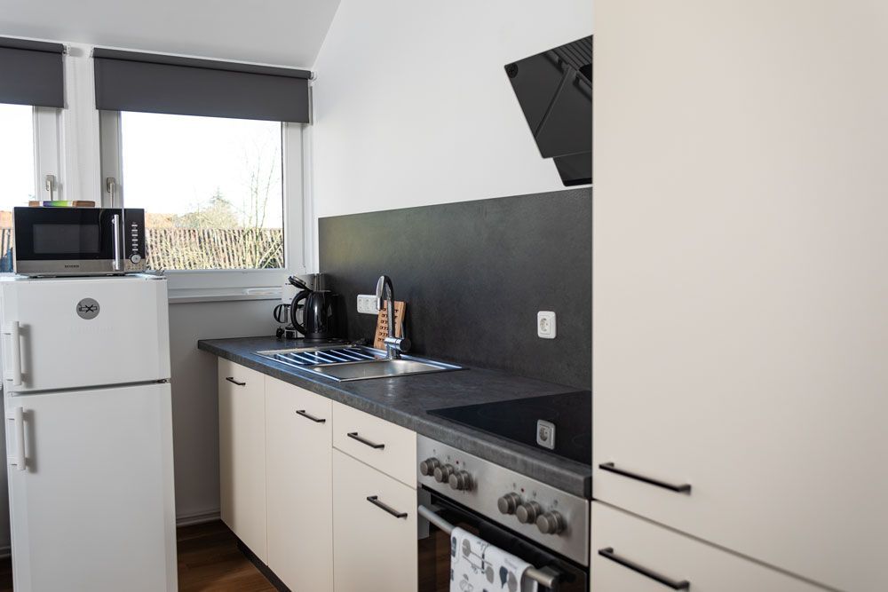 Eine Küche mit Kühlschrank, Herd, Spüle und Mikrowelle.