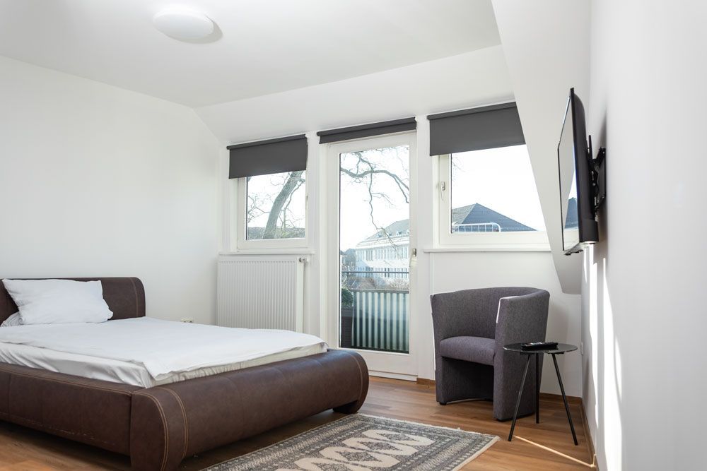 Ein Schlafzimmer mit Bett, Sessel und Fernseher