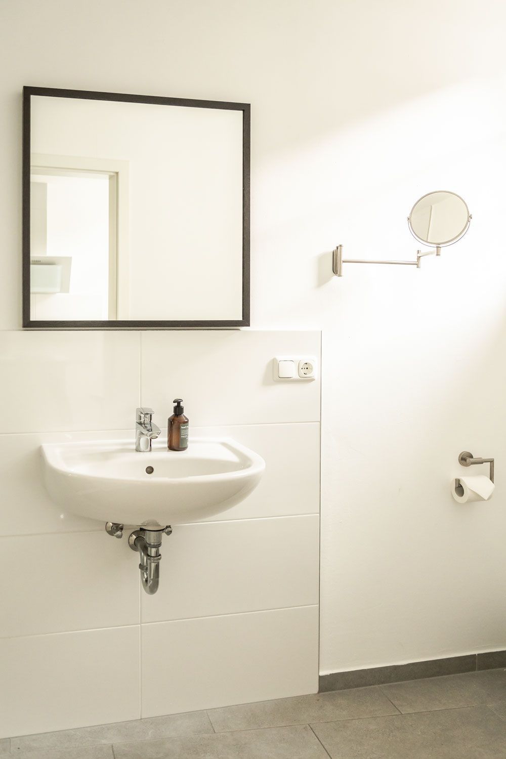 Ein Badezimmer mit Waschbecken, Spiegel und Toilettenpapier