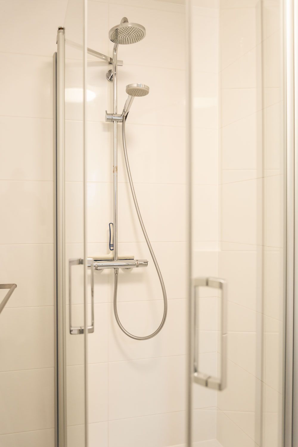 Eine Duschkabine mit Duschkopf und Schlauch in einem Badezimmer.