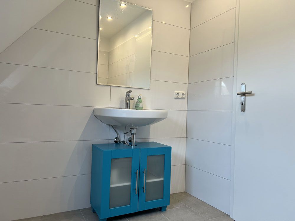 Ein Badezimmer mit Waschbecken, Spiegel und blauem Schrank