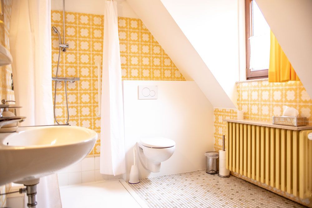 Ein Badezimmer mit Waschbecken, Toilette und gelbem Heizkörper.