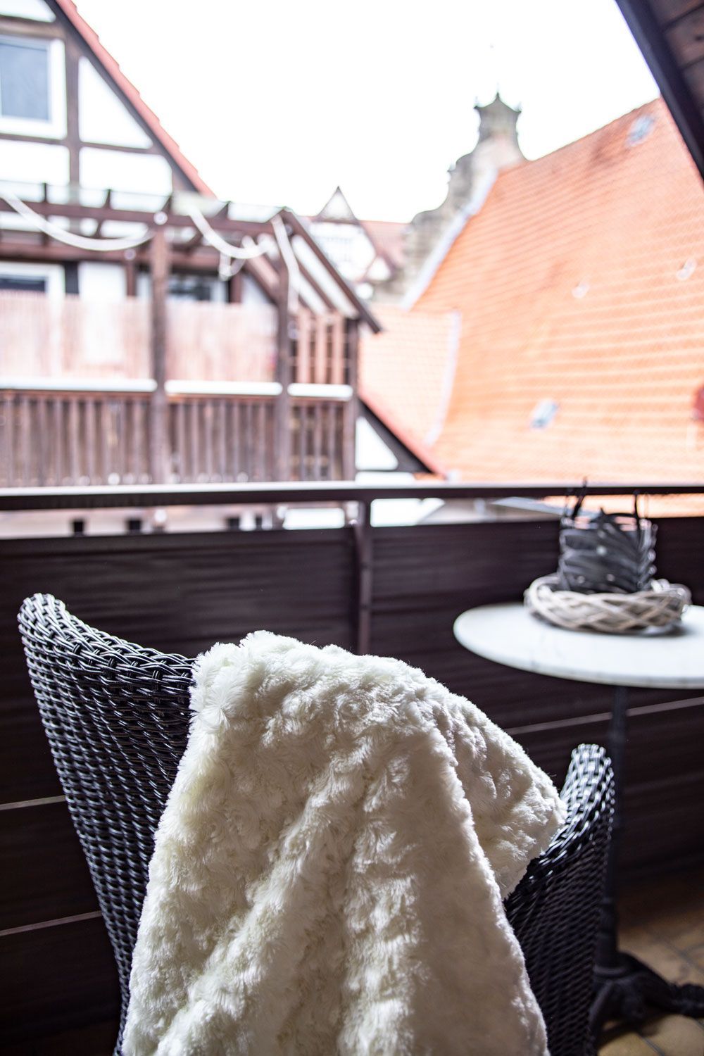 Eine weiße Decke liegt auf einem Stuhl auf einem Balkon.