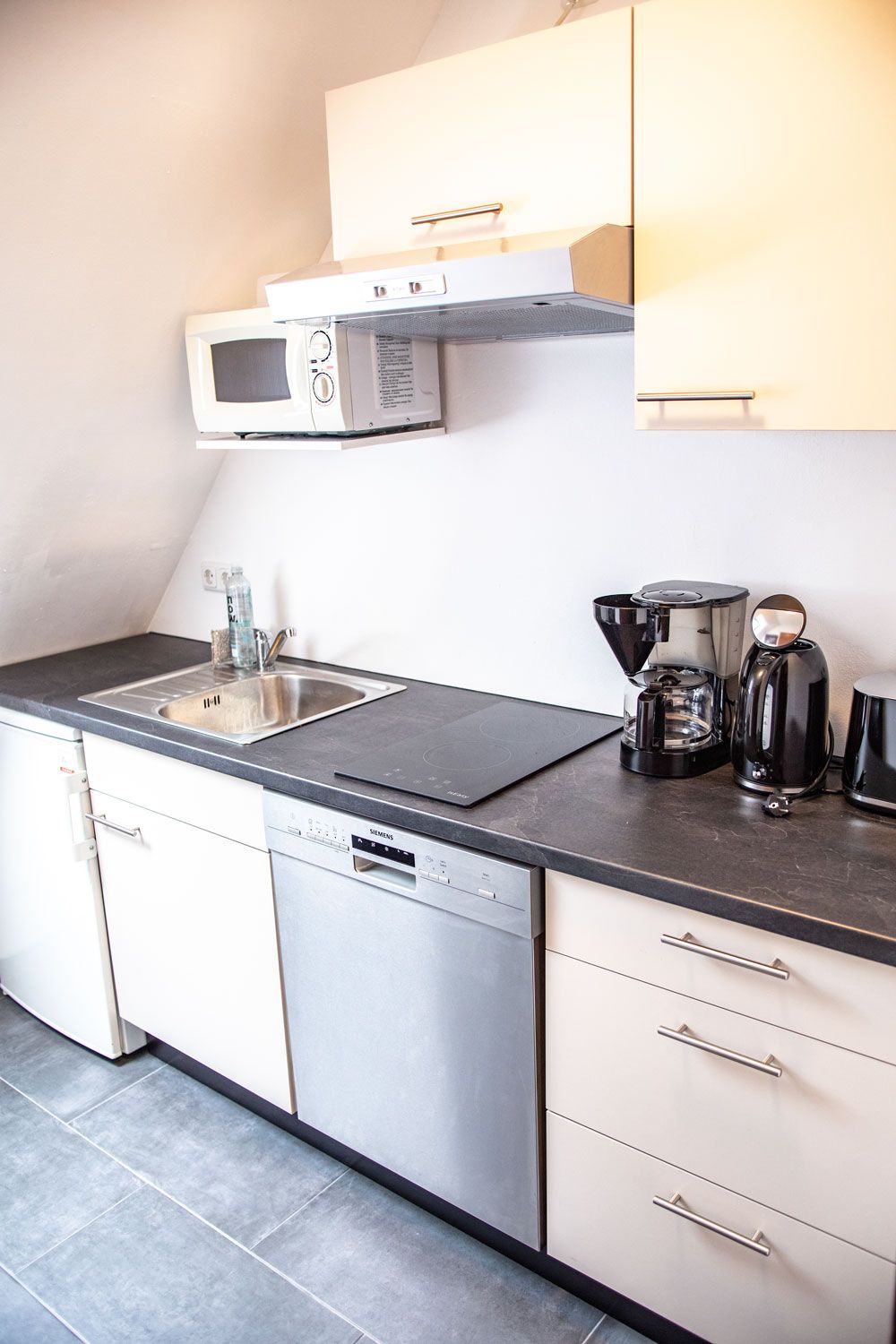 Eine Küche mit Spüle, Geschirrspüler, Mikrowelle und Kaffeemaschine.
