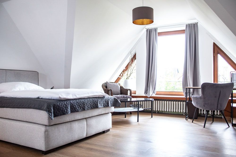 Ein Schlafzimmer mit Bett, Stuhl, Tisch und Fenster.