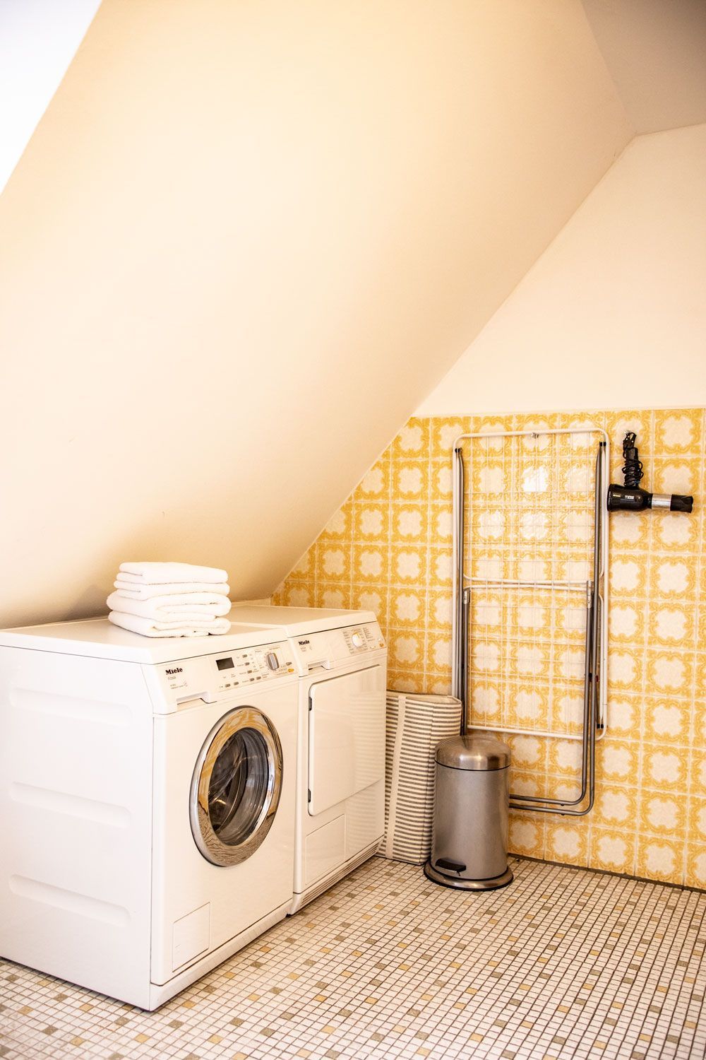 Eine Waschküche mit Waschmaschine und Trockner sowie einem Mülleimer.