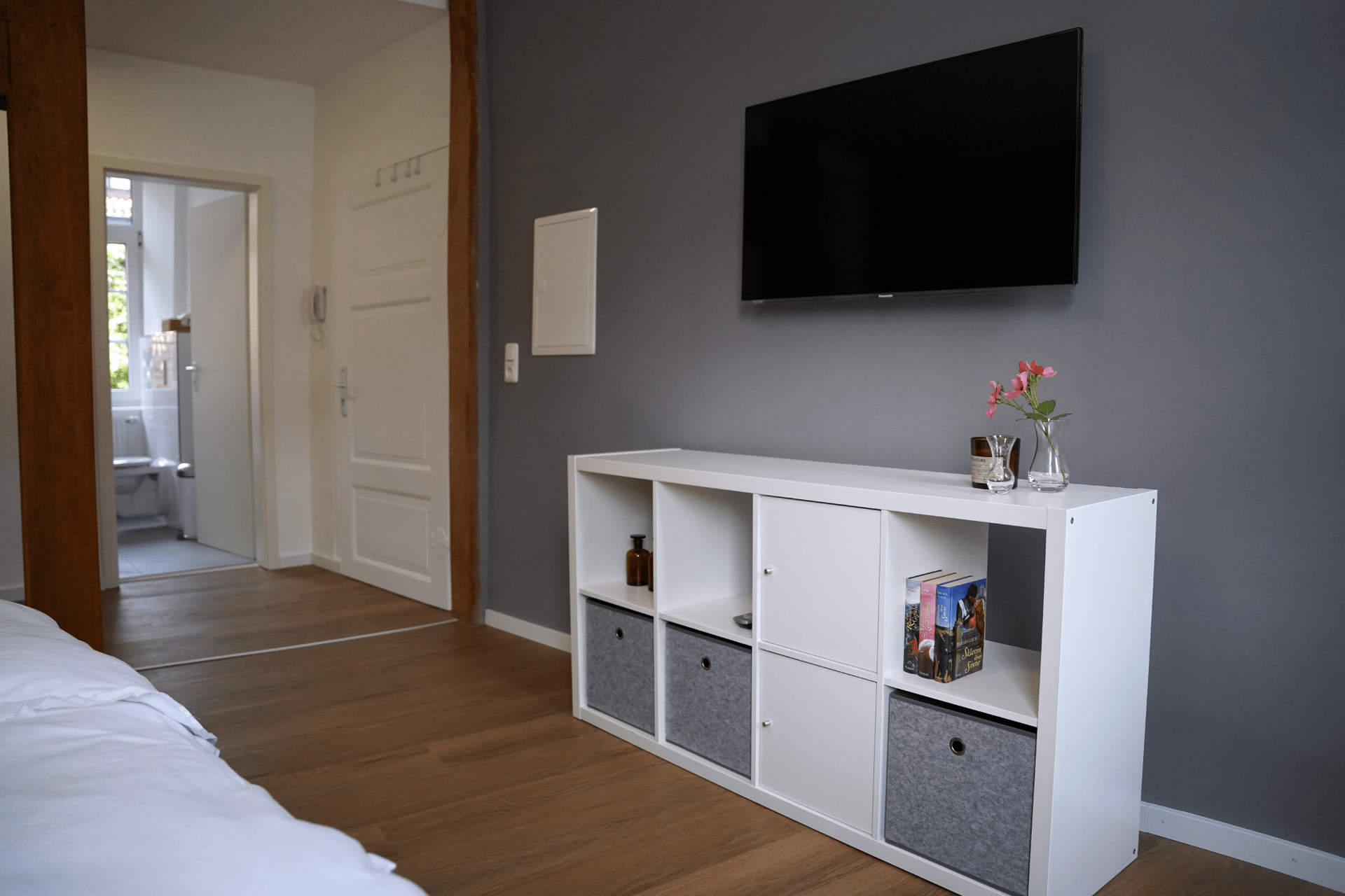 Ein Schlafzimmer mit einem Regal und einem Flachbildfernseher an der Wand.