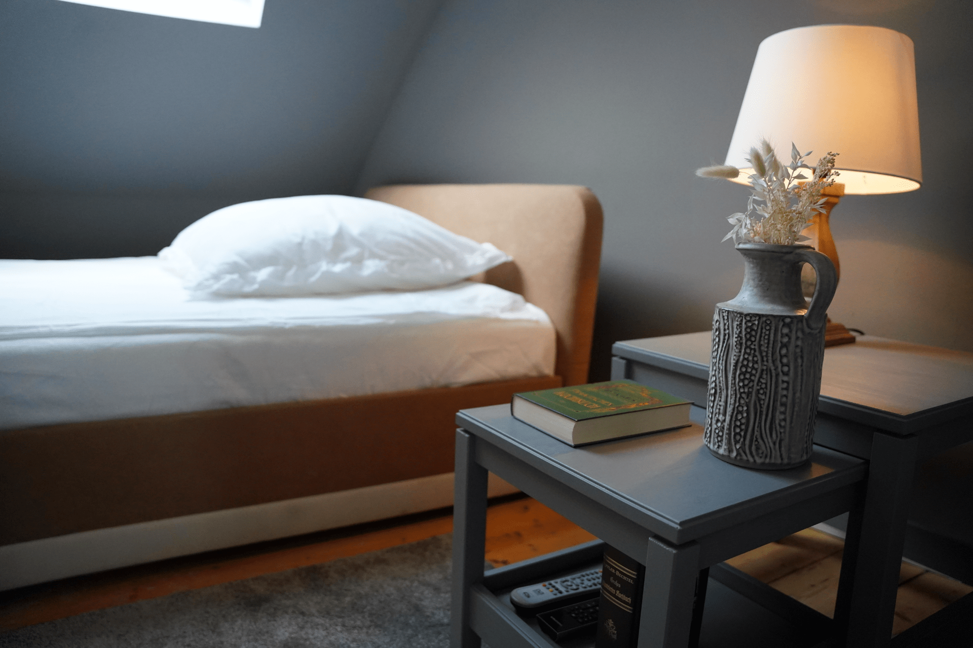 Ein Schlafzimmer mit einer Lampe und einem Buch auf einem Tisch