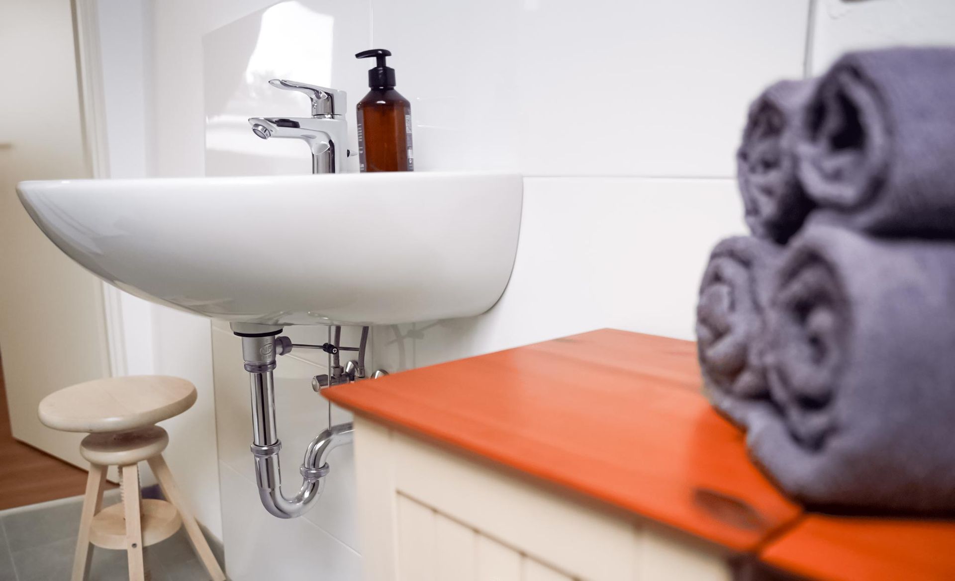 Ein Badezimmer mit Waschbecken, Seifenspender und Handtüchern auf der Ablage.