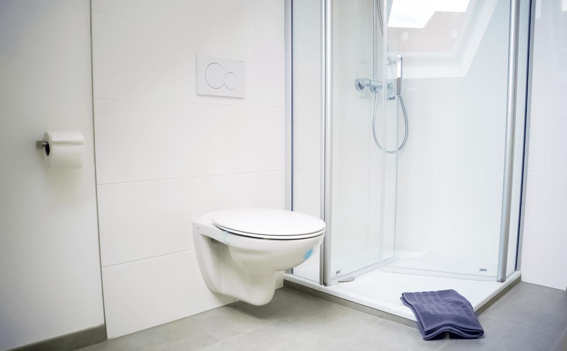 Ein Badezimmer mit Toilette, Dusche und Handtuch auf dem Boden.