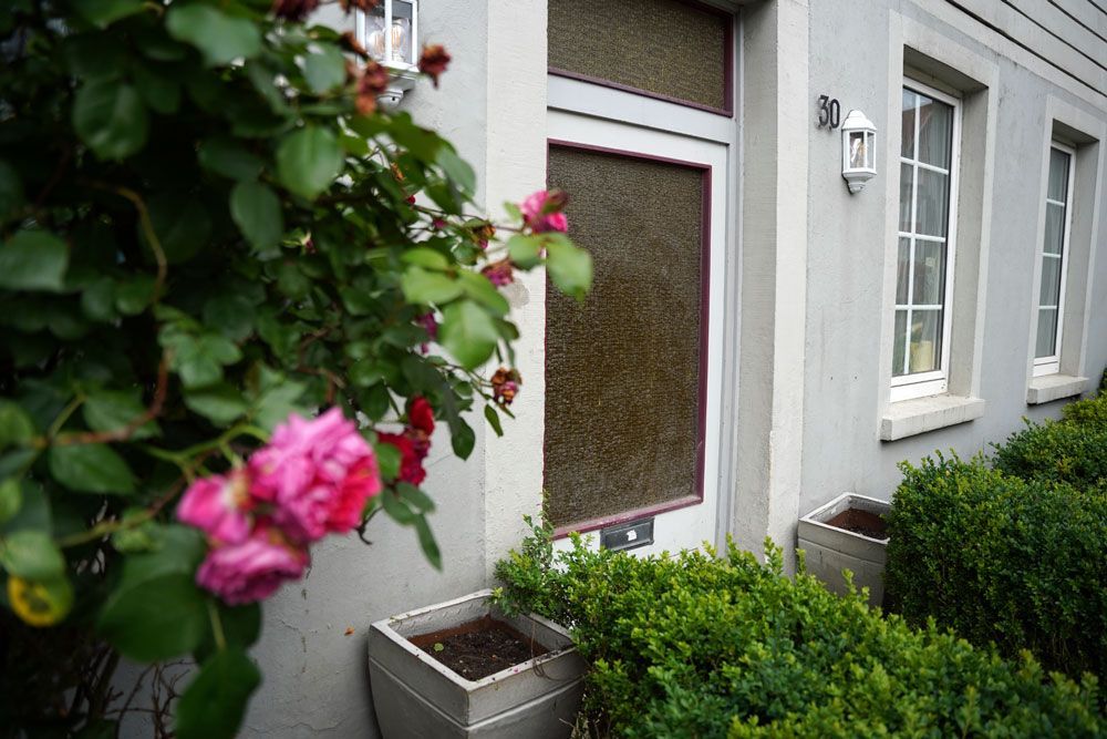 Die Haustür eines Hauses mit Blumen davor.