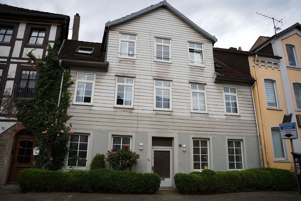 Ein großes weißes Gebäude mit vielen Fenstern und Büschen davor