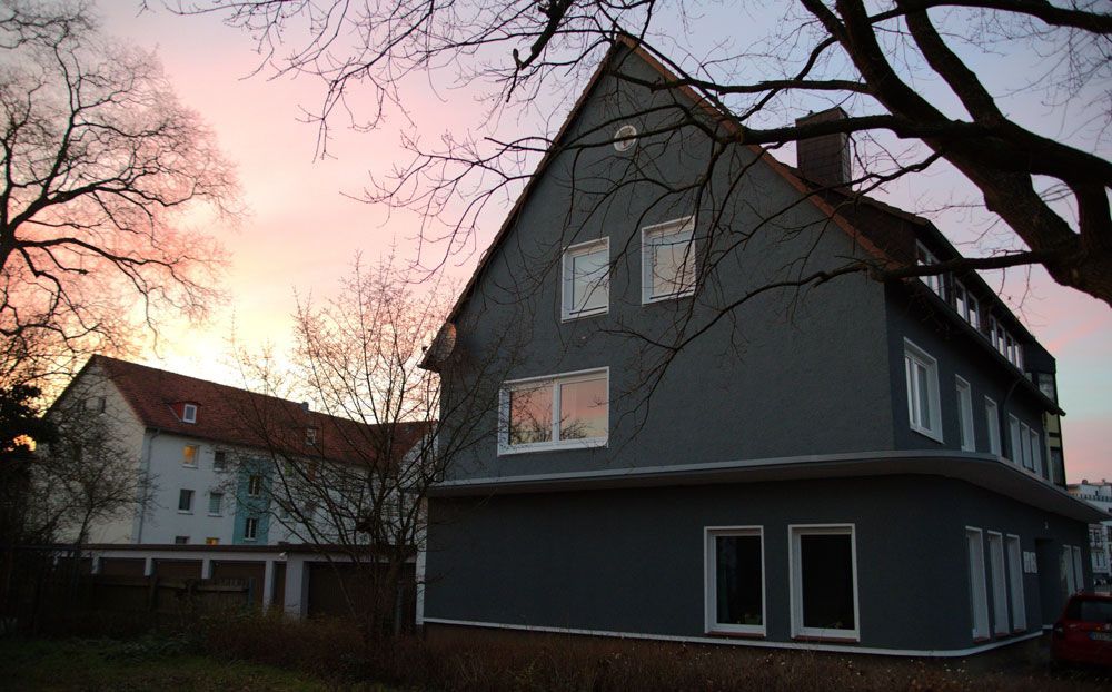 Ein Haus mit einem rosa Himmel im Hintergrund