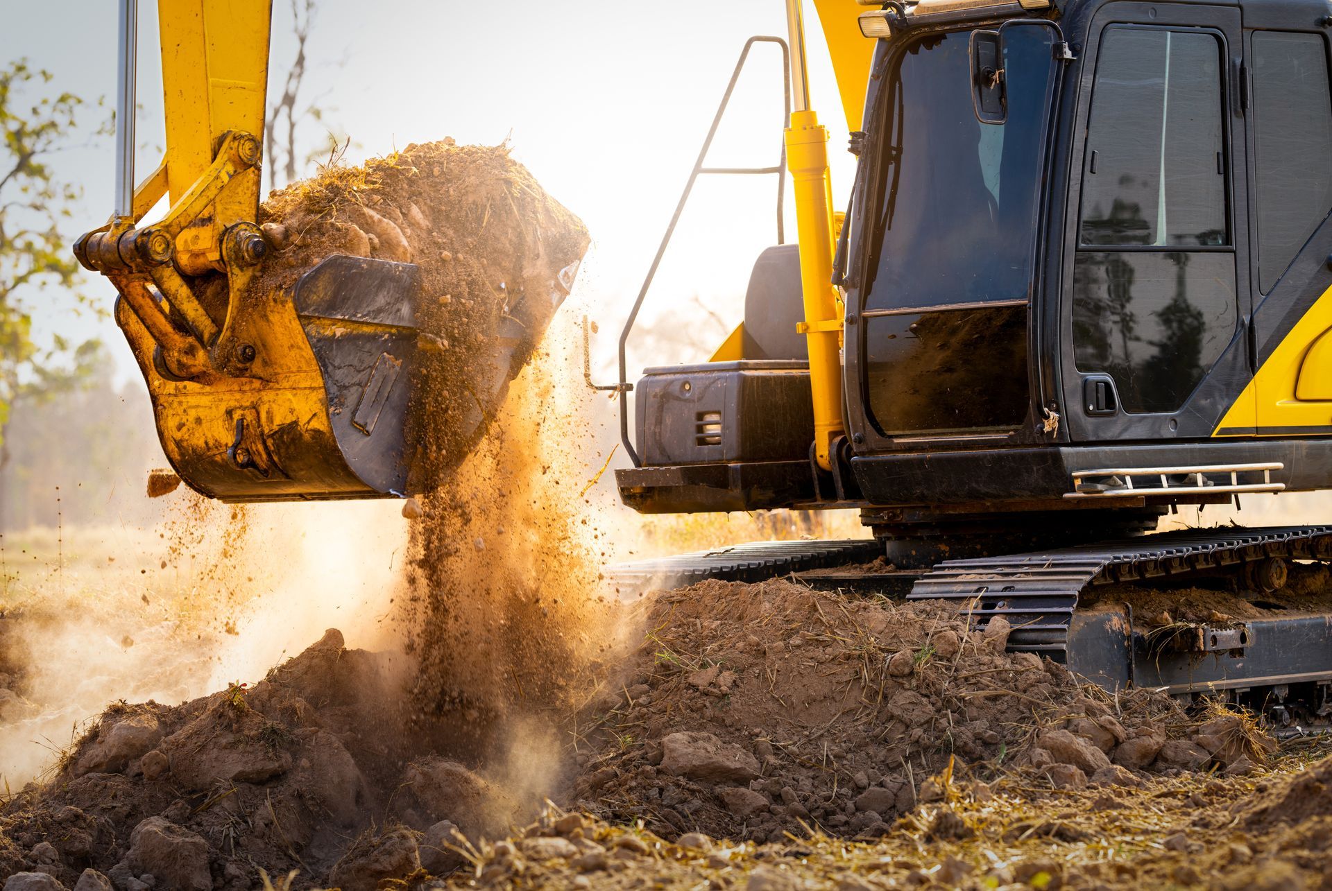 Une pelleteuse jaune creuse sur un chantier de construction, de la terre s'échappant du godet.