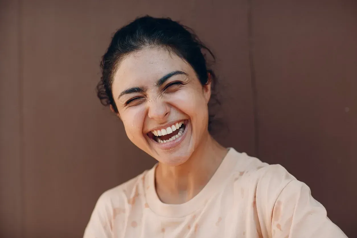 Un primer plano de una mujer riendo con los ojos cerrados.