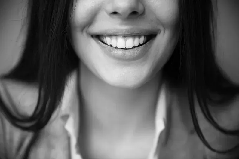 Una mujer sonríe en una foto en blanco y negro.