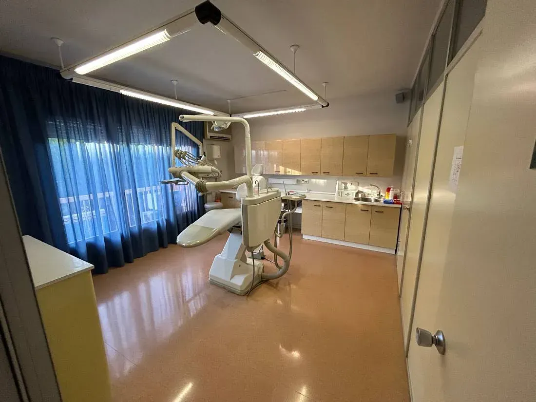 Un consultorio dental con un sillón dental y una ventana.