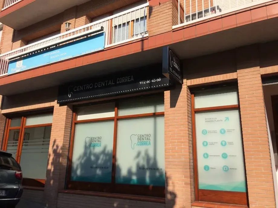 Un edificio de ladrillo con un coche aparcado delante.