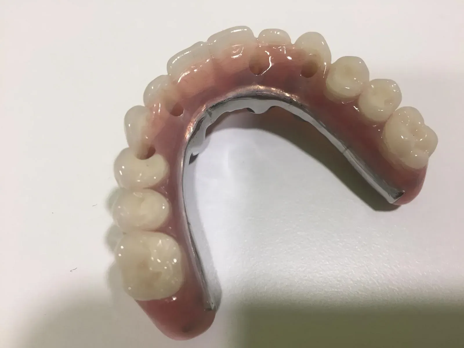Un primer plano de una dentadura postiza sobre una superficie blanca.