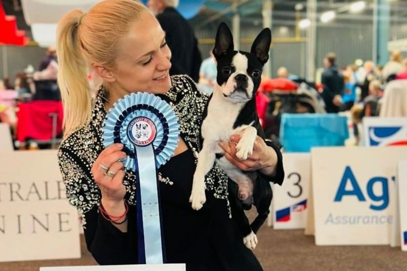 Femme blonde tenant un prix canin et portant un Boston Terrier