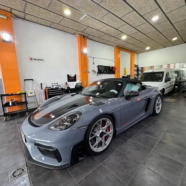 Un coche deportivo gris está aparcado en un garaje.