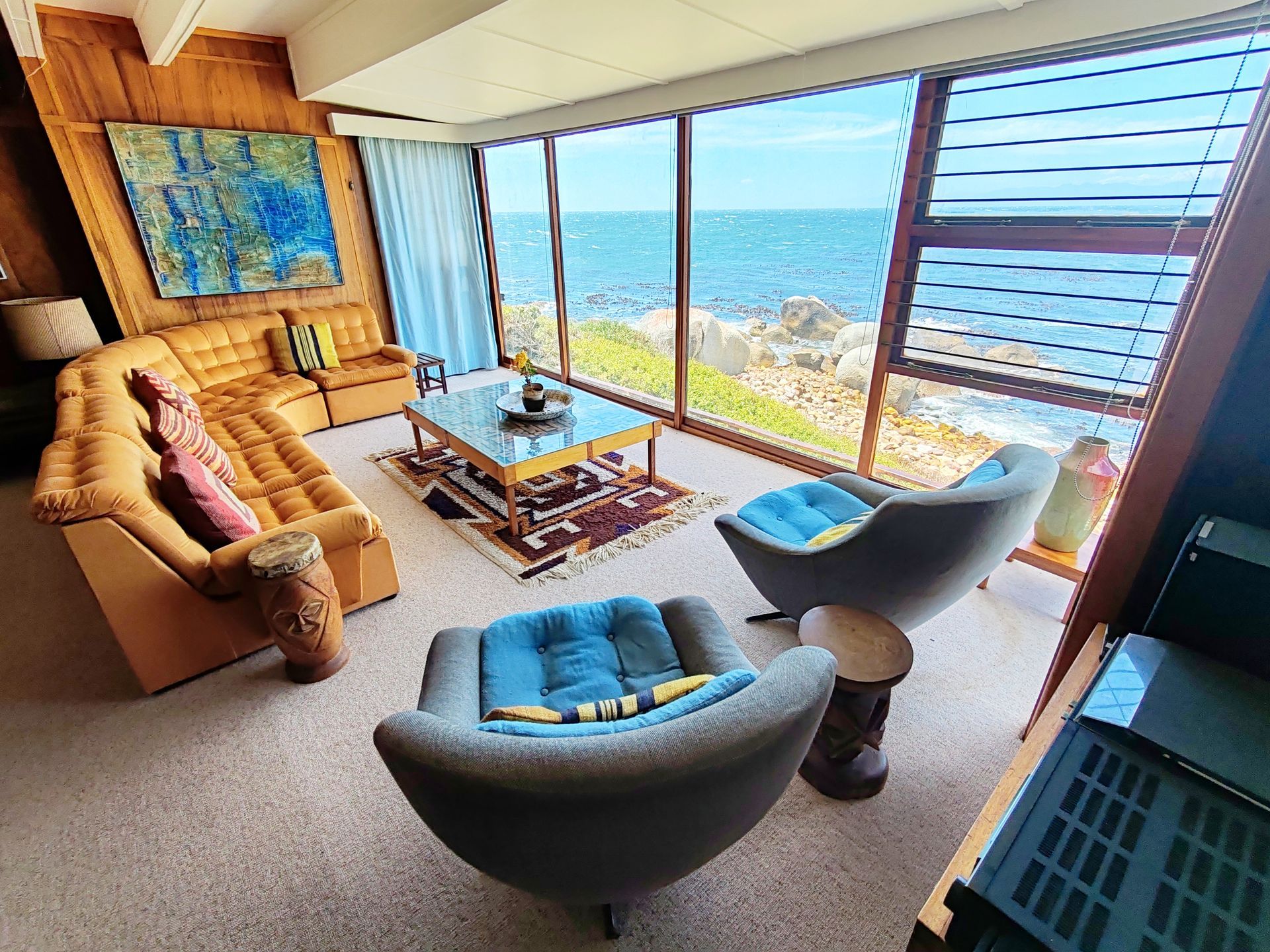 A living room with a couch , chairs and a table with a view of the False Bay ocean in Simon's Town, Cape Town